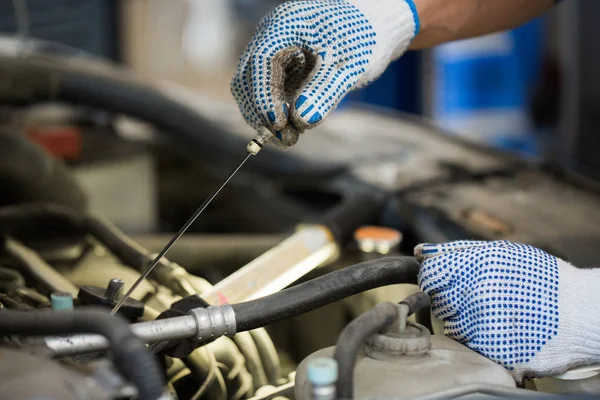 Mechanic with dipstick checking motor oil level — Stock Photo, Image