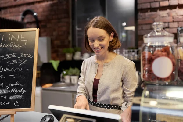 Boldog nő vagy csapos kasszával a kávézóban — Stock Fotó