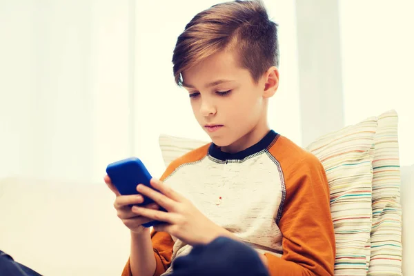 Menino com mensagens de texto smartphone ou jogar em casa — Fotografia de Stock