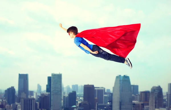 Menino em capa de super-herói vermelho e máscara voando no ar — Fotografia de Stock