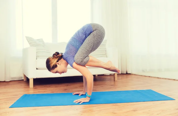 Vrouw maken van yoga in kraan pose op de mat — Stockfoto
