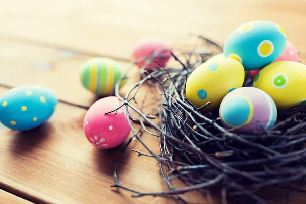 Primo piano di uova pasquali colorate in nido su legno — Foto Stock