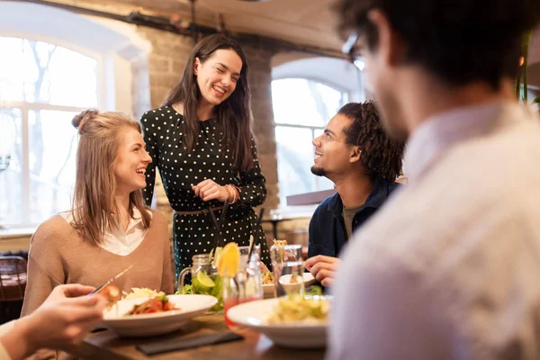 Happy friends eating and drinking at restaurant — Stock Photo, Image