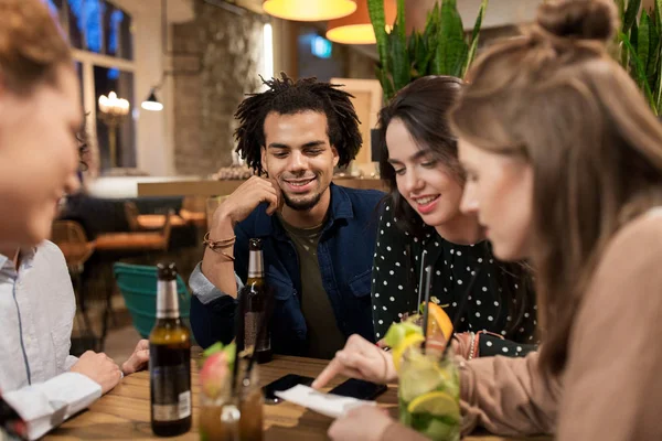 Amis heureux avec boissons et facture au bar ou café — Photo