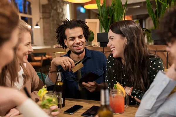 Amigos com bebidas, cartão de crédito e conta no bar — Fotografia de Stock