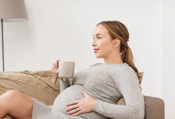 幸福的怀孕女人，坐在家里喝茶的杯 — 图库照片