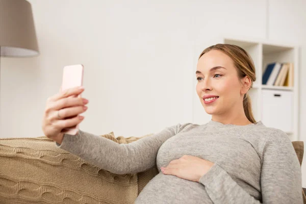 Kobieta w ciąży, biorąc smartphone selfie w domu — Zdjęcie stockowe