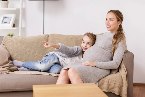 Szczęśliwy w ciąży kobieta i dziewczynka na kanapie w domu — Zdjęcie stockowe