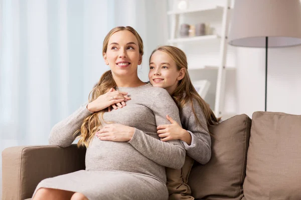 Feliz embarazada y niña abrazándose en casa — Foto de Stock