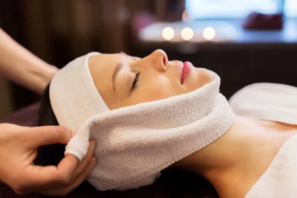 Donna con massaggio viso con asciugamano al centro benessere — Foto Stock