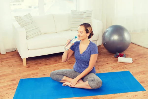 Щаслива жінка з пляшкою води тренується вдома — стокове фото