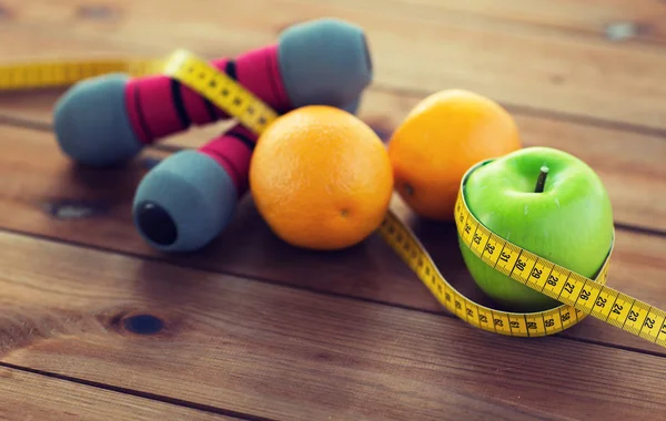 Close up of dumbbell, fruits and measuring tape — Stock Photo, Image