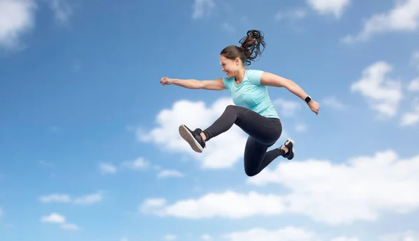 Happy smiling sporty young woman jumping in sky — Stock Photo, Image