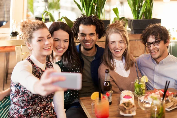 Amigos tomando selfie por smartphone no bar ou café — Fotografia de Stock