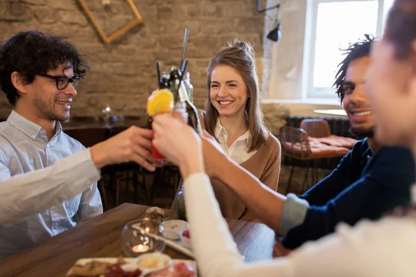 Happy vrienden rammelende drankjes in bar of café — Stockfoto