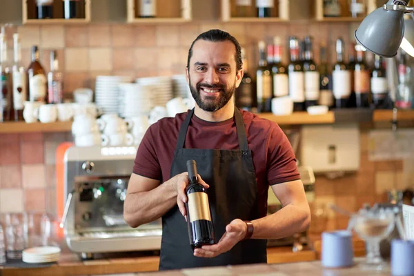 Homem feliz ou garçom com garrafa de vinho tinto no bar — Fotografia de Stock