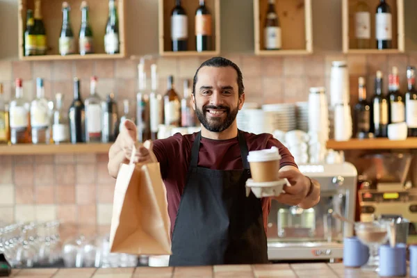 Homem ou garçom com café e saco de papel no bar — Fotografia de Stock