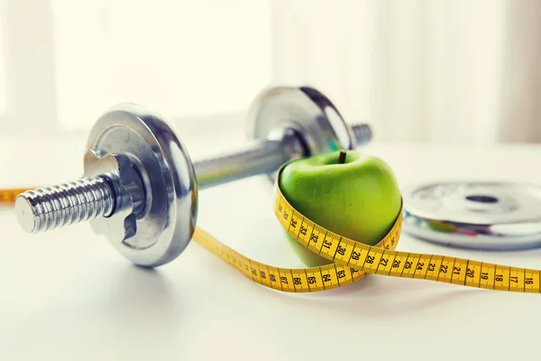 Close up of dumbbell and apple with measuring tape — Stock Photo, Image