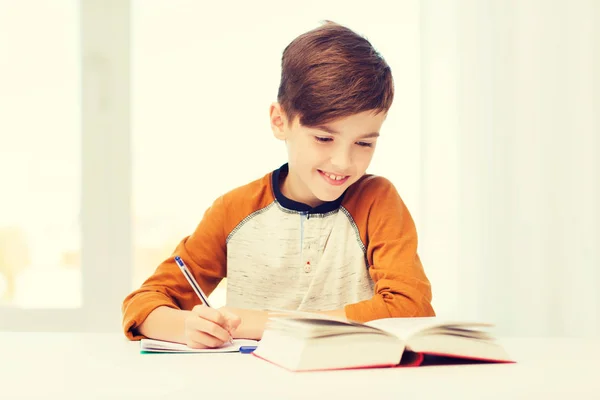 Усміхнений студентський хлопчик пише в блокнот вдома — стокове фото