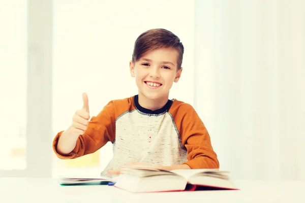 Menino estudante feliz com livro mostrando polegares para cima — Fotografia de Stock