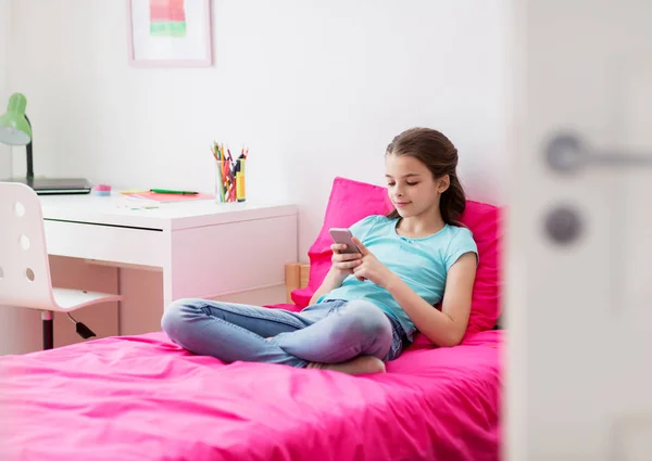 Smiling girl texting on smartphone at home — Stock Photo, Image