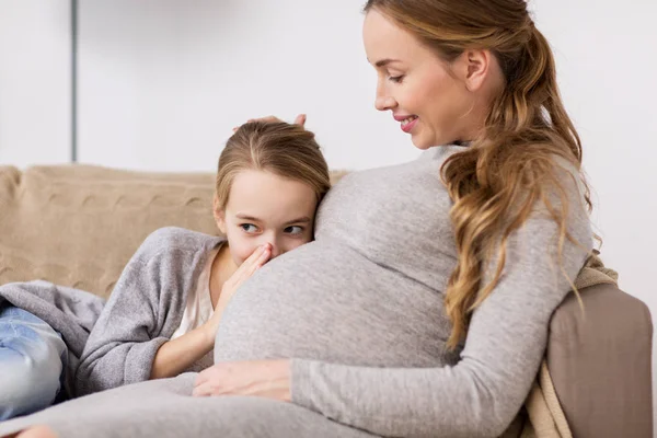 Pregnant woman and girl talking to baby in belly — Stock Photo, Image