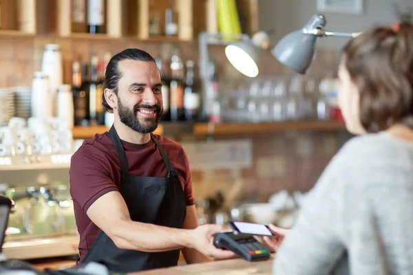 Barman i kobieta z czytnika kart i smartphone — Zdjęcie stockowe