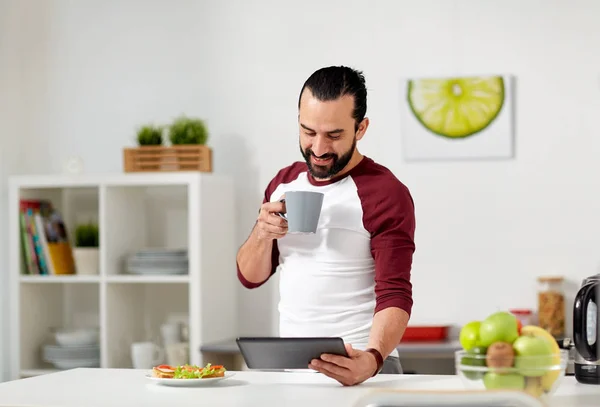 Człowiek z komputera typu tablet w domu jedzenie kuchnia — Zdjęcie stockowe