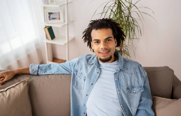 Felice uomo afro americano sorridente sul divano di casa — Foto Stock