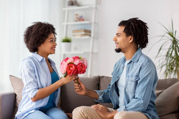 Feliz pareja con ramo de flores en casa — Foto de Stock