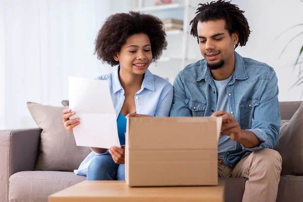 Couple heureux avec boîte de colis et formulaire papier à la maison — Photo