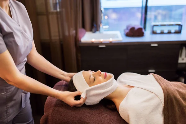 Vrouw met gezicht massage met handdoek op spa salon — Stockfoto