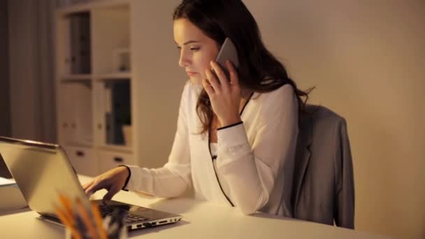 Donna con computer portatile che chiama su smartphone in ufficio — Video Stock