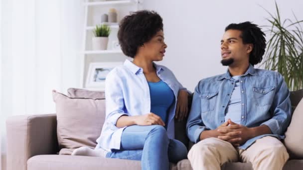 Счастливая пара, сидящая на диване и разговаривающая дома — стоковое видео