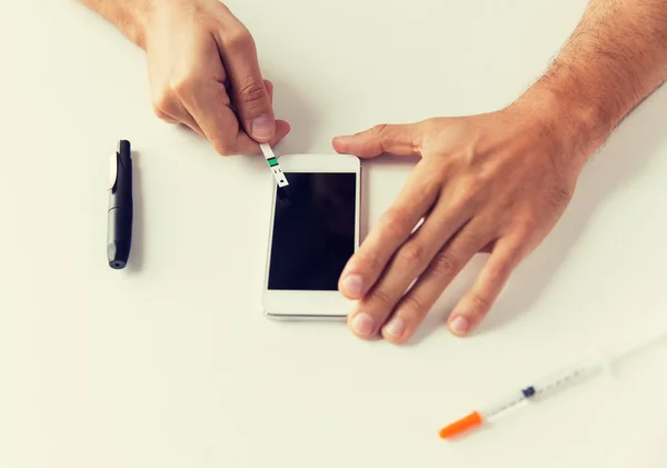 Primo piano dell'uomo con smartphone fare esami del sangue — Foto Stock