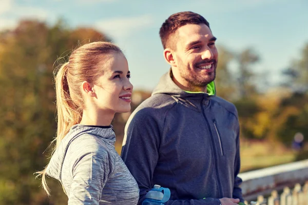 Pareja sonriente con botellas de agua al aire libre —  Fotos de Stock