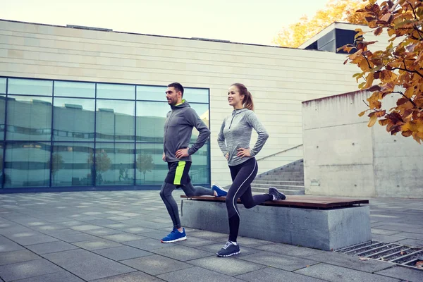 Happy man and woman exercising on bench outdoors — Stock Photo, Image