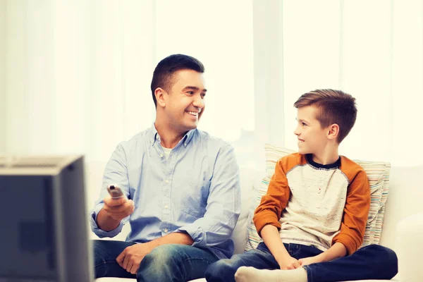 Leende far och son tittar på tv hemma — Stockfoto