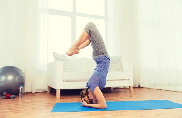 Kobieta robi jogę w pozycji headstand na macie — Zdjęcie stockowe