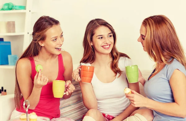 Mujeres jóvenes felices bebiendo té con dulces en casa — Foto de Stock