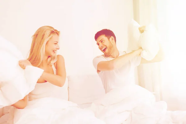 Счастливая пара, дерущаяся подушками в постели дома — стоковое фото