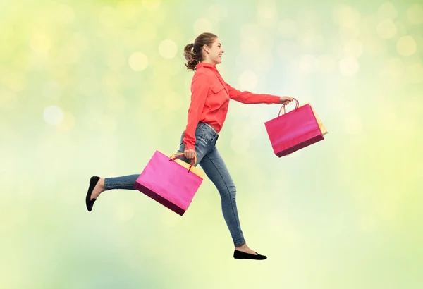 Souriant jeune femme avec des sacs à provisions en cours d'exécution — Photo