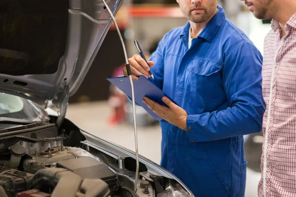 Automechaniker mit Klemmbrett und Mann im Autohaus — Stockfoto