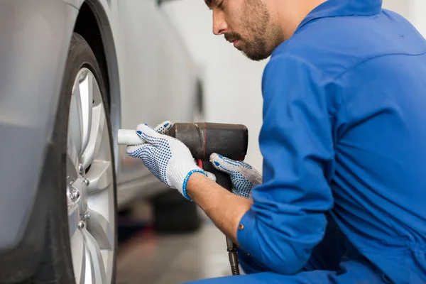 Mecânico com chave de fenda trocando pneu do carro — Fotografia de Stock