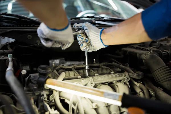 Mechaniker mit Schraubenschlüssel repariert Auto in Werkstatt — Stockfoto