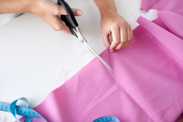 Woman with tailor scissors cutting out fabric — Stock Photo, Image