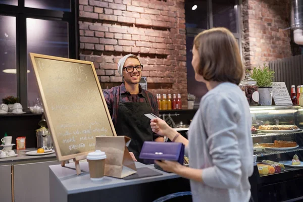 Barman y mujer pagando con tarjeta de crédito en la cafetería — Foto de Stock
