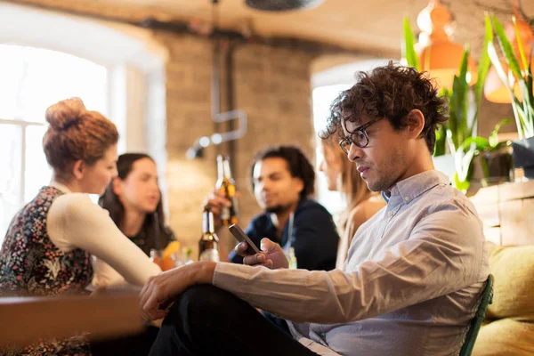 Hombre con smartphone y amigos en el restaurante — Foto de Stock