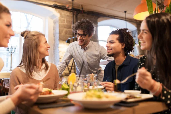 Amigos felizes comendo e bebendo no restaurante — Fotografia de Stock