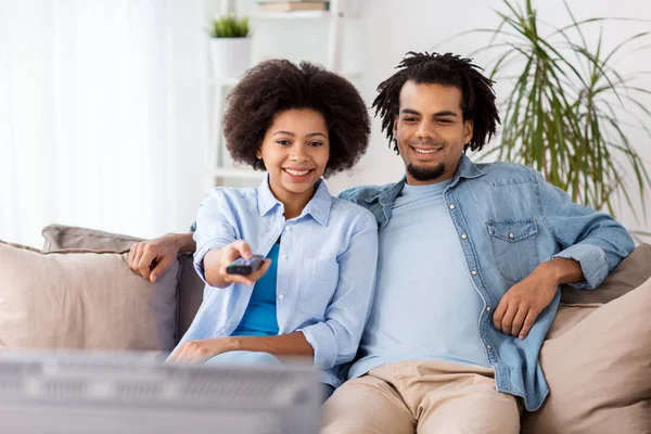 Smiling couple with remote watching tv at home — Stock Photo, Image